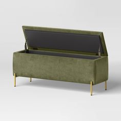 an upholstered green bench with gold legs and a black seat cushion on top