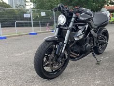 a black motorcycle is parked on the side of the road in front of a fence