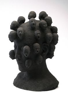 a black sculpture with lots of small balls on it's head, against a white background