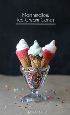 three ice cream cones with sprinkles in a small glass cup on a table