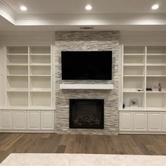 an empty living room with built in bookshelves and fireplace