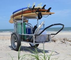 a cart filled with surfboards on top of a sandy beach next to the ocean