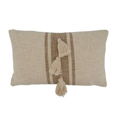 a brown and white striped pillow with two tassels on the front, one in beige