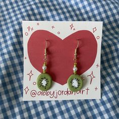 a pair of green and white earrings sitting on top of a card