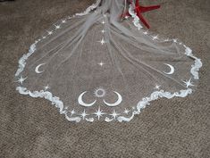 a white veil with stars and moon designs on it sitting on the floor next to a red chair