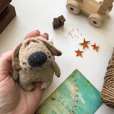 a person holding a small stuffed dog in their hand next to other items on the table