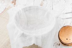 a wooden bowl sitting on top of a table next to a white cloth covered cup