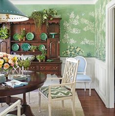 a dining room with green walls and floral wallpaper on the walls, along with white chairs