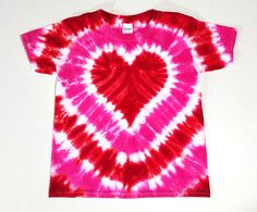 a pink and red tie - dyed shirt with a heart on the front, sitting on a white surface