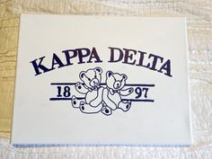 the logo for kappa delta is shown on a white quilted bed sheet