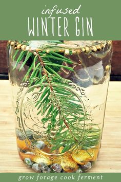 a mason jar filled with pine needles and other things sitting on top of a wooden table