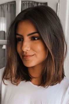 a woman with long hair is smiling at the camera while wearing a white t - shirt