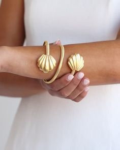 Wrap your wrist with one of the most coveted styles from the late 60s and 70s. Inspired by fabulous women and their best accessories, our Marbella Wrap Bangle is all you need to dress up your every day. Unique in shape and lightweight to wear, it’s the perfect piece to jazz up your jewelry box. Looking closely, you’ll notice that the textured look of the band comes from an intricate design of small diamond-shaped indentations. Made complete with the Marbella Shell pendant at each end, this brace Elegant Metal Bangle For Spring, Chic Metal Cuff Bracelet, Chic Evening Bracelet Jewelry, Retro Jewelry For Parties, Chic Evening Jewelry Bracelet, Chic Evening Bracelets, Adjustable Jubilee Bracelet For Evening, Spring Party Bracelet Jewelry, Chic Evening Bangle Jewelry