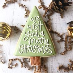 a decorated christmas tree cookie sitting on top of a table next to pine cones and decorations