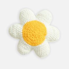 a crocheted flower brooch in yellow and white, on a white background