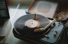 an old record player sitting on top of a suitcase