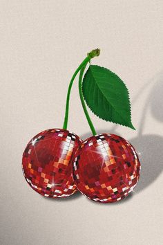 two red cherries with green leaves on top of them, sitting next to each other