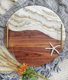 a wooden plate with seashells and starfish on it next to dried grass