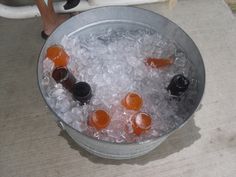 an ice bucket filled with bottles of beer on top of a sidewalk next to a person