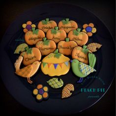 decorated cookies on a black plate with words and pumpkins in the center that spell out their names