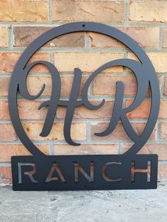 a metal ranch sign sitting next to a brick wall