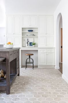 a kitchen with white cabinets and an island in the middle is seen from across the room