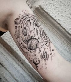 an arm tattoo with planets and stars on the outer half of it, in black ink