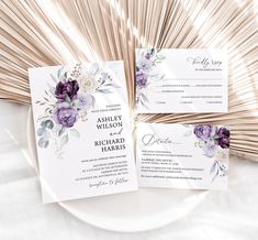 wedding stationery with purple flowers and greenery on white plate next to bamboo fan