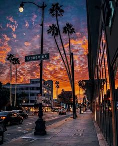 the sun is setting behind palm trees on an urban street in los angeles, california