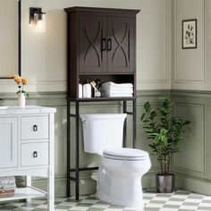 a white toilet sitting in a bathroom next to a wooden cabinet and potted plant