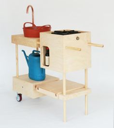 a small wooden cart with a blue watering can and a red pot on it's side