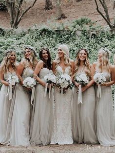 a group of women standing next to each other wearing dresses and holding bouquets in their hands