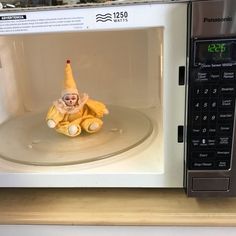 a microwave oven with a toy clown sitting on top of it