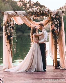 a man and woman standing on top of a wooden dock