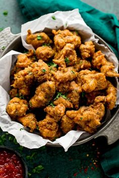 a bowl filled with fried chicken and garnished with parsley next to ketchup