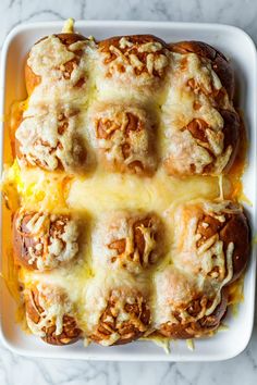 baked bread covered in cheese and nuts on a white platter with a marble counter top