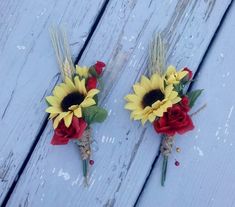 two fake sunflowers and red roses are placed next to each other on a wooden surface