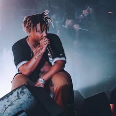 a man with dreadlocks on his head sitting in front of a microphone at a concert