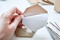 a person is cutting out some paper with scissors and other crafting supplies on the table