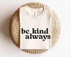 a t - shirt that says be kind of always on it next to a wicker basket