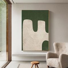 a chair and ottoman in front of a painting on the wall next to a window