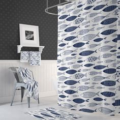 a blue and white shower curtain with fish on it next to a chair in a bathroom