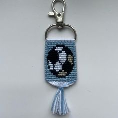 a blue and white keychain with an animal on it's side, hanging from a metal hook