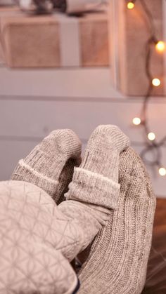 a pair of mittens sitting on top of a wooden table next to a christmas tree