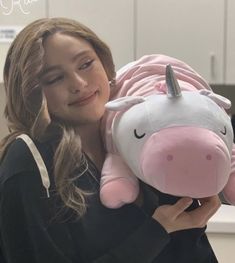 a woman holding a pink and white stuffed unicorn