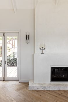 an empty living room with a fireplace and french doors