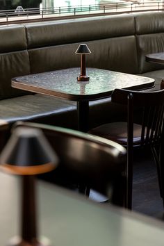 tables and chairs in a restaurant setting with a lamp on the table next to them