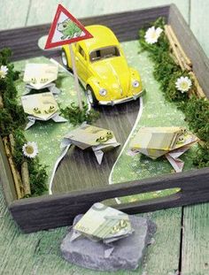 a yellow car is parked on the road in front of a sign with flowers and grass