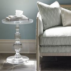 a glass table sitting on top of a floor next to a white couch and chair