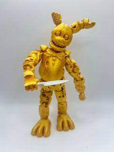 a yellow toy holding a knife in it's hand